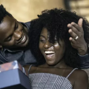 Man giving woman a gift at home, which has major benefits for happiness and illustrates the power of giving