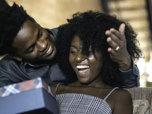 Man giving woman a gift at home, which has major benefits for happiness and illustrates the power of giving