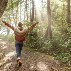 Woman with arms raised enjoying the mental health benefits of spending time in nature