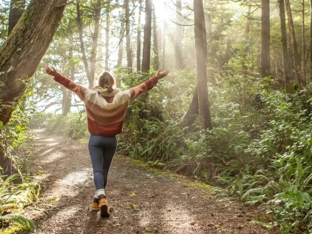 Woman with arms raised enjoying the mental health benefits of spending time in nature