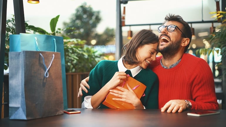 Happy couple laughing exchanging gifts for the holidays