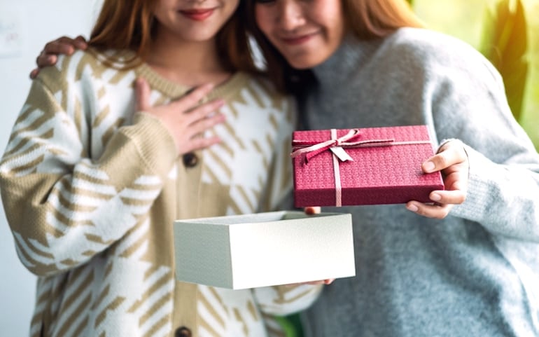 Friends exchanging presents, as giving to others can benefit your self-esteem