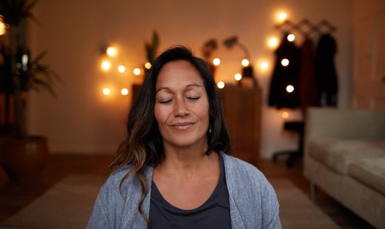 Serene woman practicing mindfulness at home for less stress, more happiness, and better emotional health