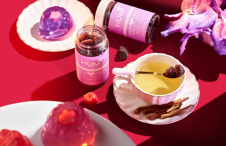 Calm Sweet Calm stress gummies on a pink, red, and purple table setting with tea