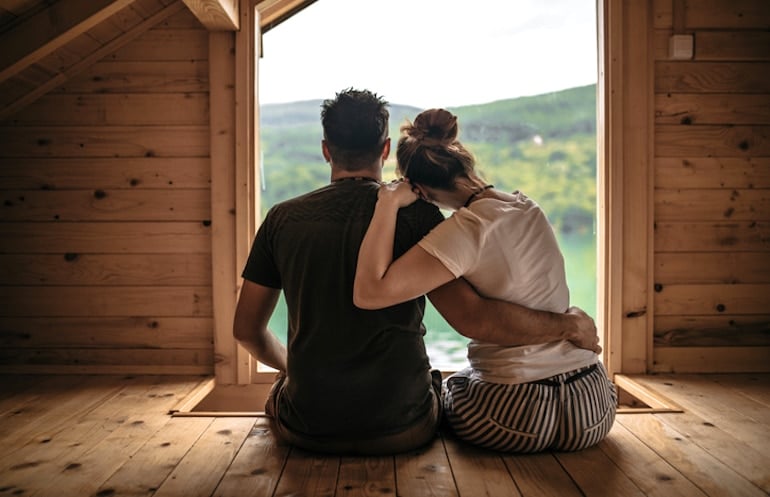 Young couple embracing in a cabin in the middle of nature to get away from the city and reduce stress