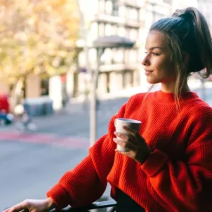 Woman enjoying coffee on her balcony, observing nature and the benefits of staying present