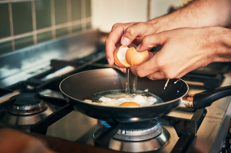 Man cooking eggs to get enough protein to balance hormones naturally