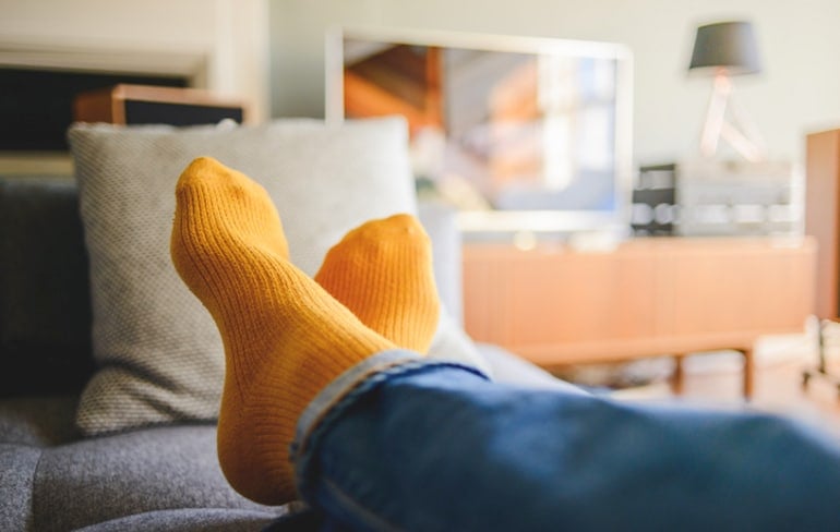 Shot of person's feet up on couch to illustrate staying present by taking breaks