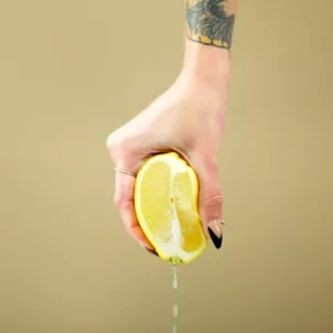 Woman squeezing a lemon on plain background; normal vaginal discharge concept