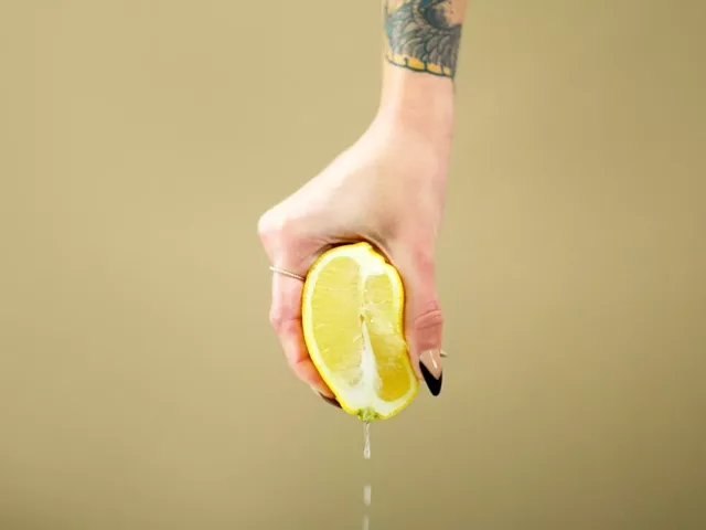 Woman squeezing a lemon on plain background; normal vaginal discharge concept