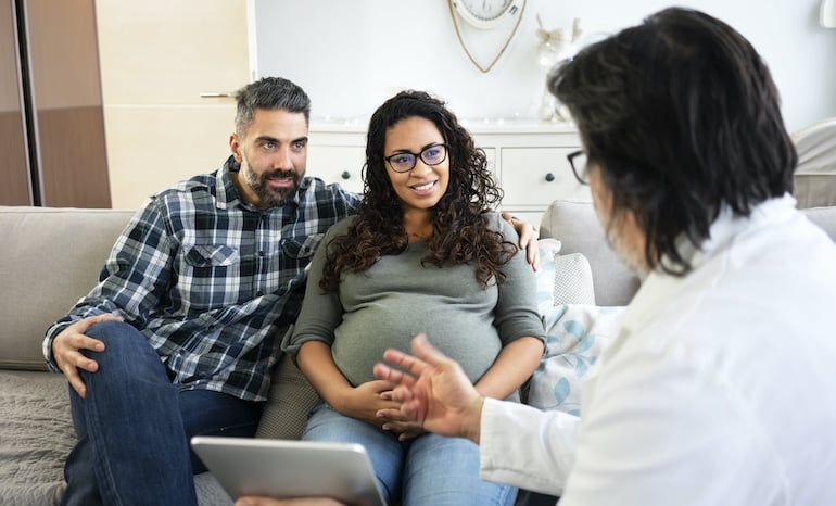 Pregnant couple at doctor to discuss healthy supplements during pregnancy