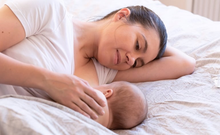 Woman nursing her baby in bed