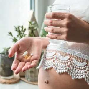 Pregnant woman taking vitamin with water