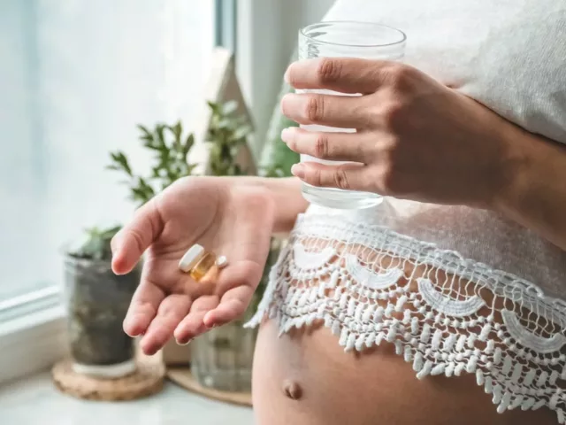 Pregnant woman taking vitamin with water