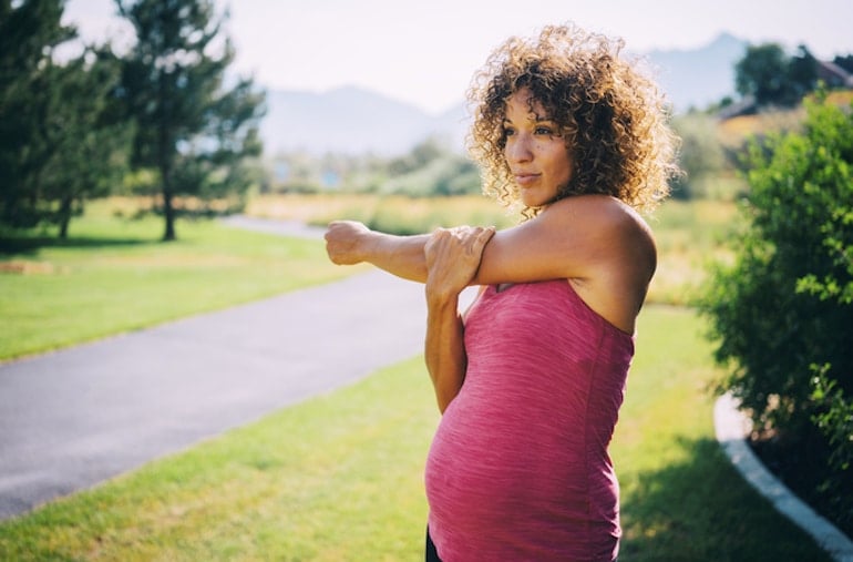 pregnant woman stretching and getting vitamin D from the sun