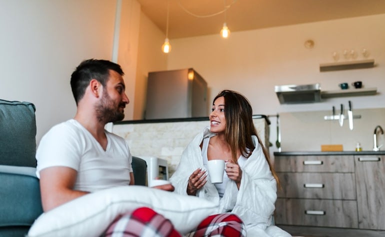 Couple sitting in living room under weighted blanket to ease stress