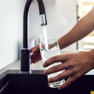 Close up of man getting a glass of water from the kitchen sink since he knows it's important to stay hydrated