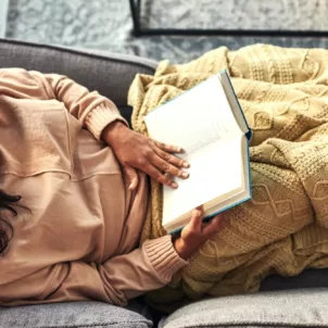 Woman reading a book on the couch as a stress reduction technique