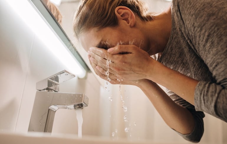 Woman washing her face with gentle glycolic and lactic acids