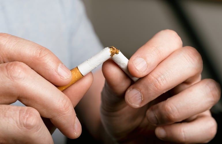 Man breaking a cigarette since smoking doesn't align with his healthy identity