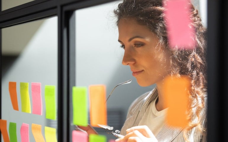 Woman using post-its on wall to plan good habits for success