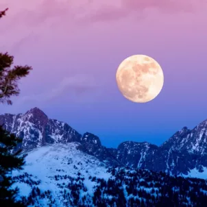 Beautiful winter night sky of purple, pink, and blue hues with a full moon