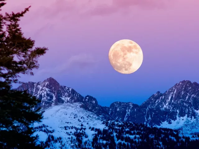 Beautiful winter night sky of purple, pink, and blue hues with a full moon