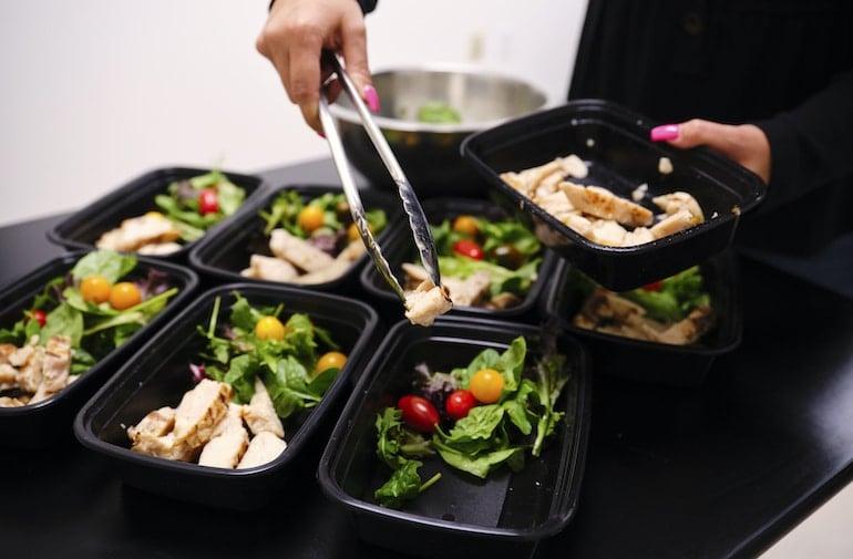 Woman meal prepping healthy salads with chicken to establish good nutrition habits