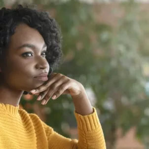 Pensive woman sitting at desk, wondering how long it takes to build a habit