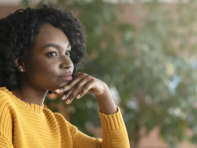 Pensive woman sitting at desk, wondering how long it takes to build a habit