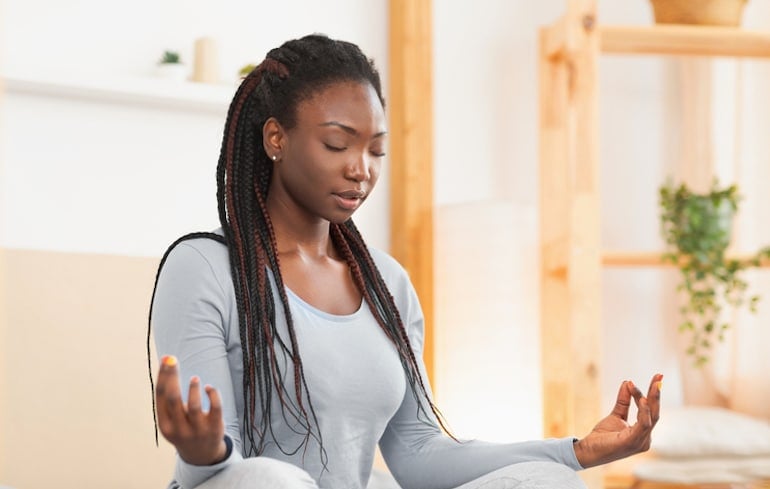 Woman meditating with eyes closed in the morning on her bed