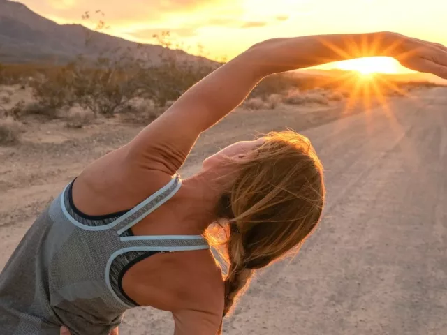 Woman stretching at sunset, with working out as her goal to form badass habits