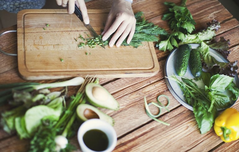 Person chopping a salad with dark leafy greens to help get rid of stress belly