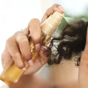 Woman spraying oil onto her ends to perfect her curly hair wash day routine