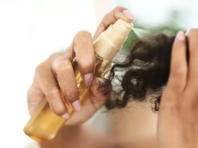 Woman spraying oil onto her ends to perfect her curly hair wash day routine