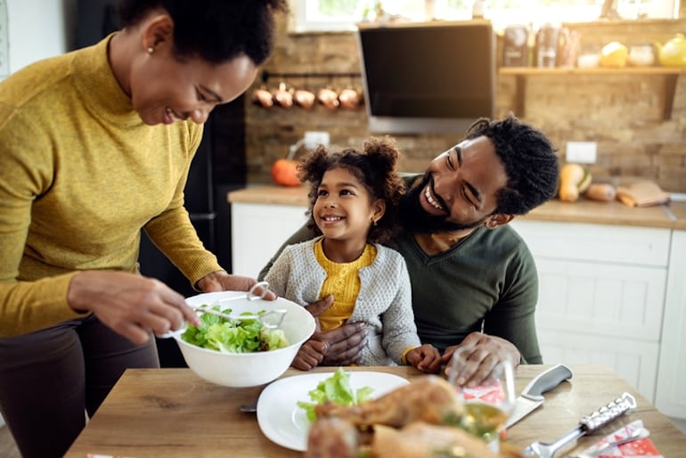 Family of three enjoying dinner, mindful eating, and other benefits of self-care with food and relationships