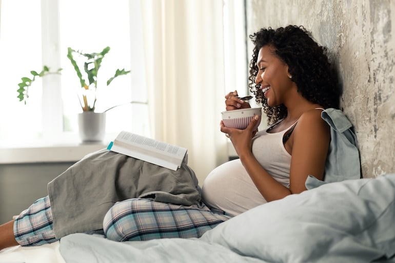 Pregnancy woman in bed eating breakfast to meet her nutrition needs during pregnancy