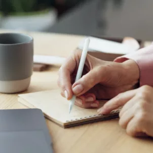 Woman writing down a to do list at work