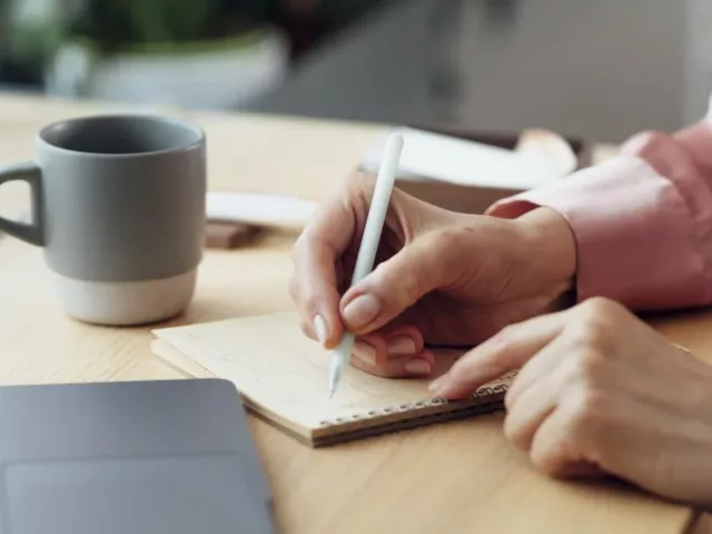 Woman writing down a to do list at work