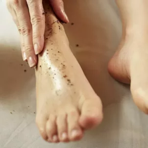 Woman exfoliating her dry, cracked feet with an exfoliating scrub