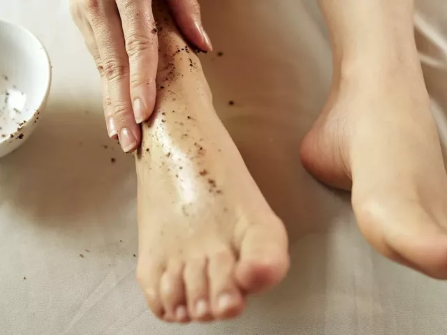 Woman exfoliating her dry, cracked feet with an exfoliating scrub