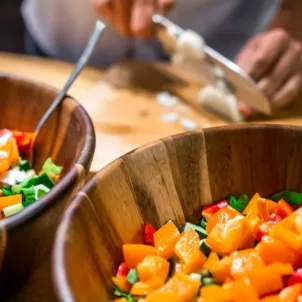 Man chopping vegetables for a low-fat diet salad, which may lead to unwanted side effects like cravings and mood imbalances