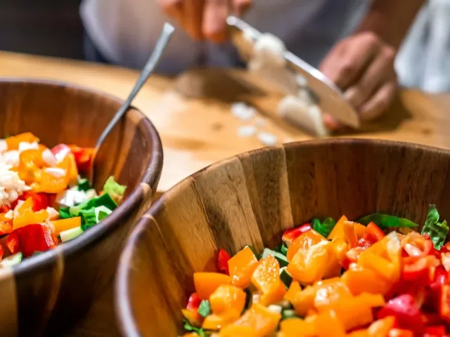 Man chopping vegetables for a low-fat diet salad, which may lead to unwanted side effects like cravings and mood imbalances