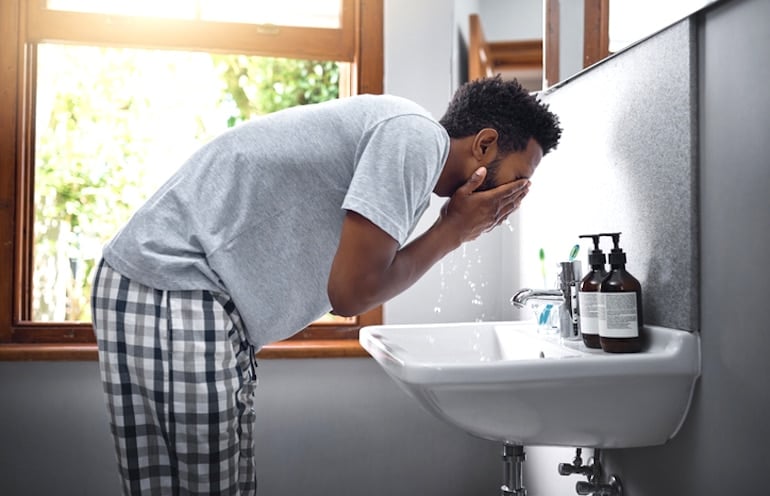 Man washing his face with gentle, simple products to deal with skin purging breakouts