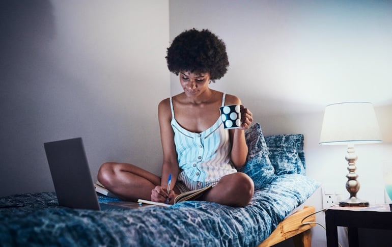 Woman practicing intuitive eating to stop her habit of snacking at night; using tea and journaling to promote healthy habits