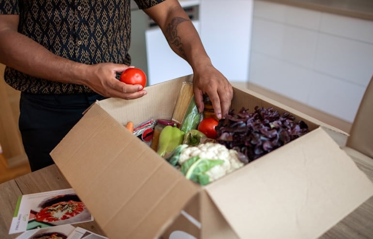 Man unpacking healthy grocery deliver as a strategy to stop late-night snacking