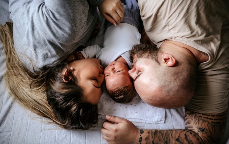 New parents co-sleeping with newborn baby