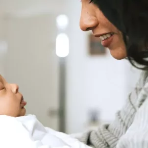 Mother holding newborn and prioritizing postpartum self-care