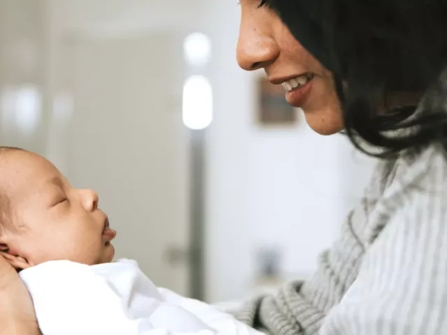 Mother holding newborn and prioritizing postpartum self-care