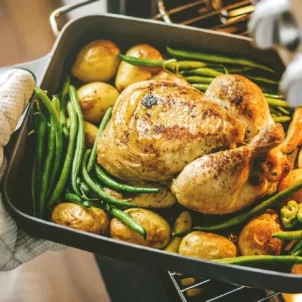 Dietitian taking a one-pan meal of chicken, green beans, and potatoes out of the oven as part of her mindful eating dinner plan